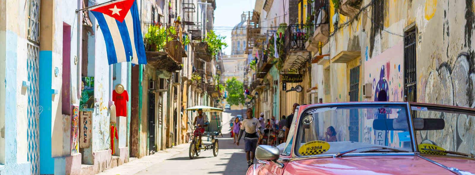 oude straat havana met roze auto en cubaanse vlag