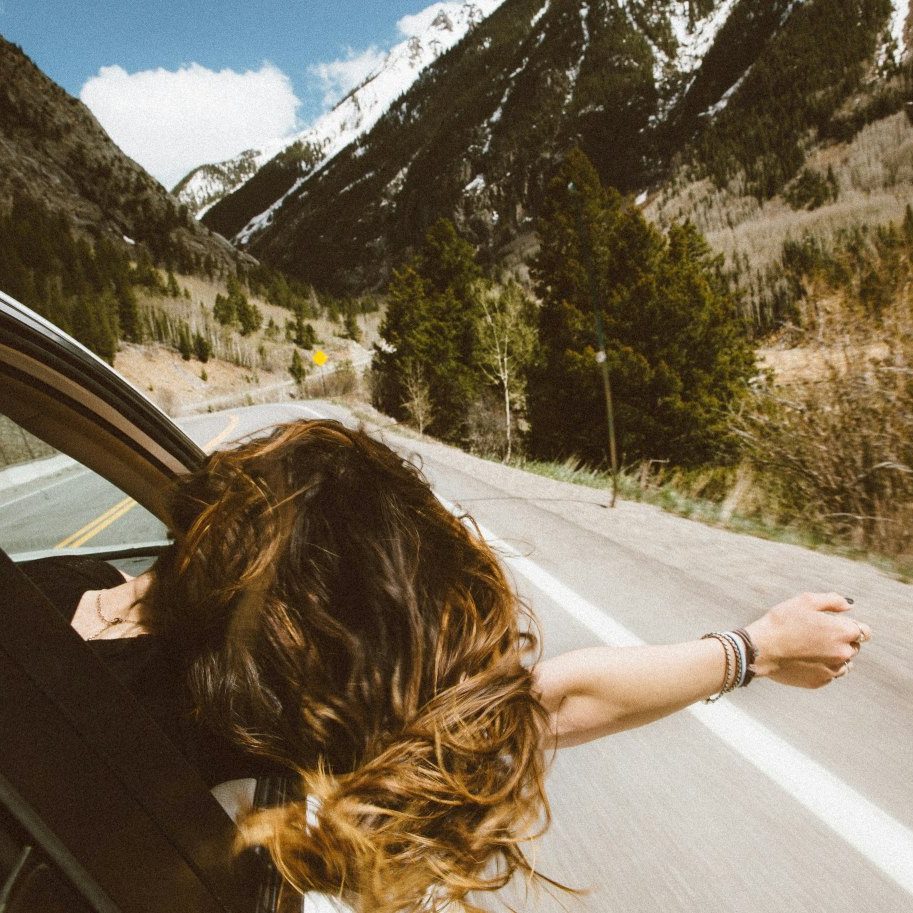 Roadtrip-vrouw-met-wapperende-haren-uit-het-raam