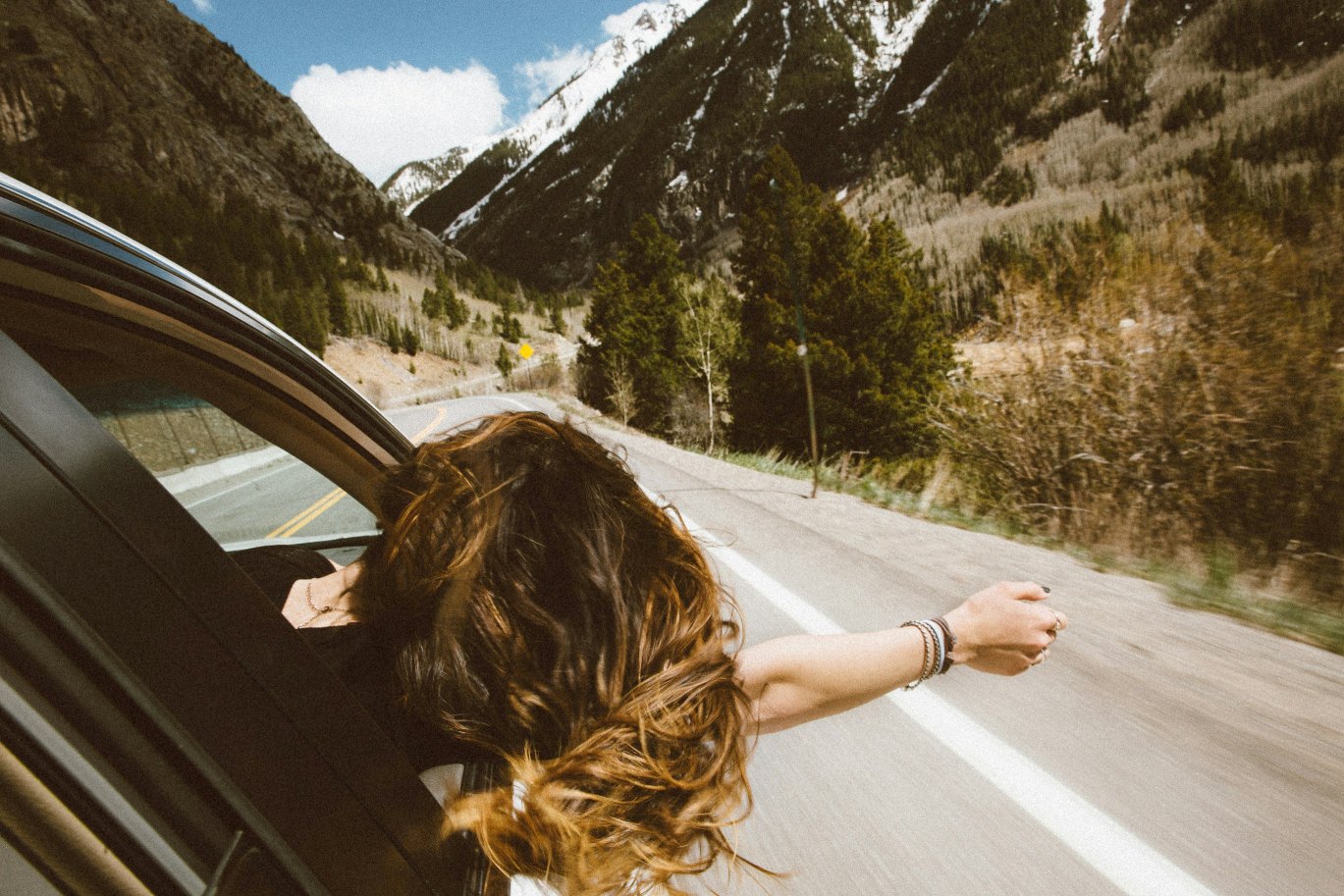 Roadtrip vrouw met wapperende haren uit het raam