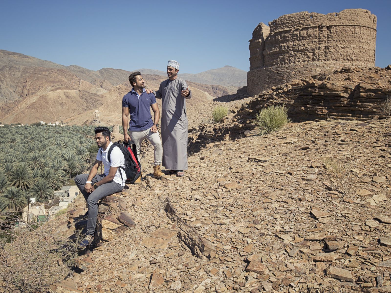 Rondreis Oman, Birkat Al Mouz, mensen naast een ruïne van een toren