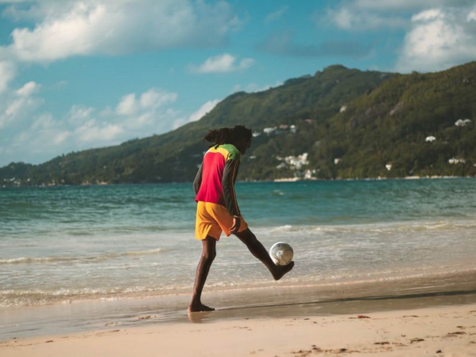 Rondreis Seychellen, Mahé, persoon met een voetbal op het strand