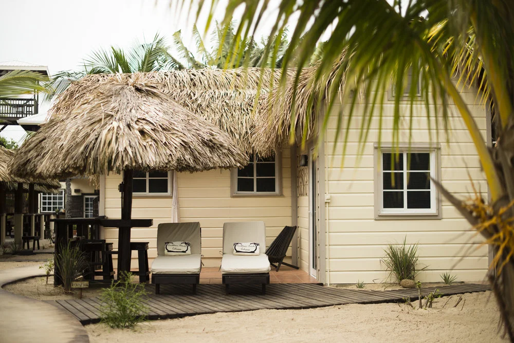 Rondreis Belize, Placenia, Carribean Beach Cabanas, La Casita ligstoelen met parasol