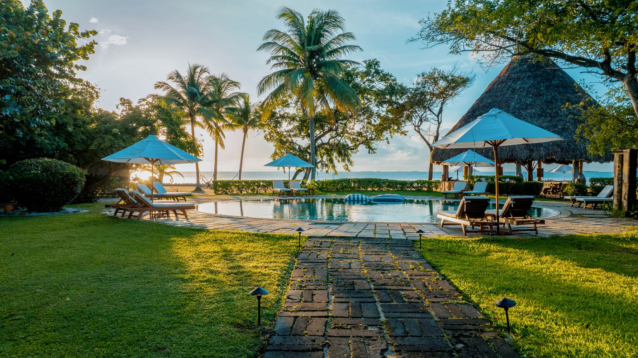 Rondreis Belize, Placenia, Turtles Inn, zwembad met stoelen en parasols