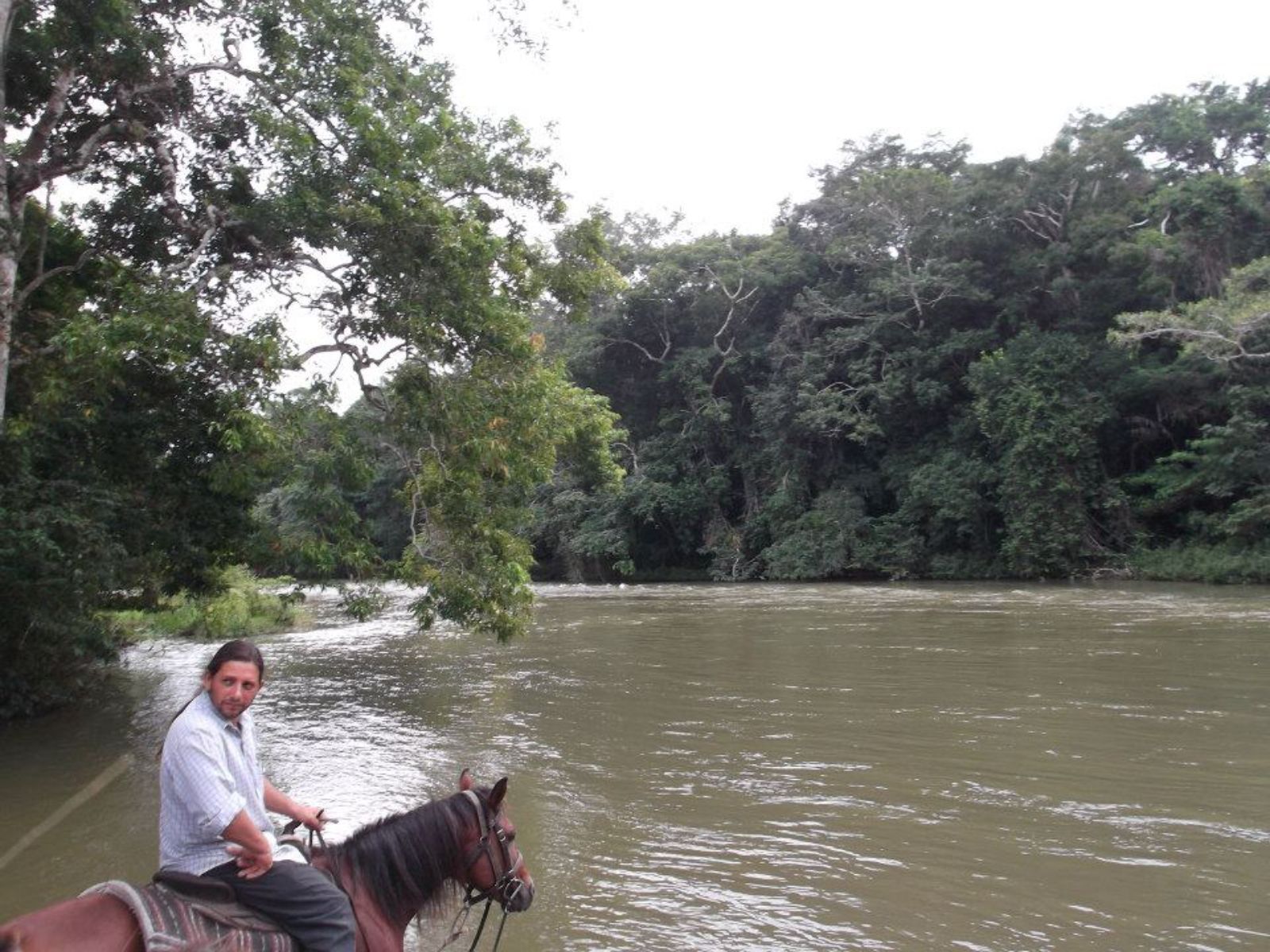 Rondreis Belize, San Ignacio, man op paard bij meer
