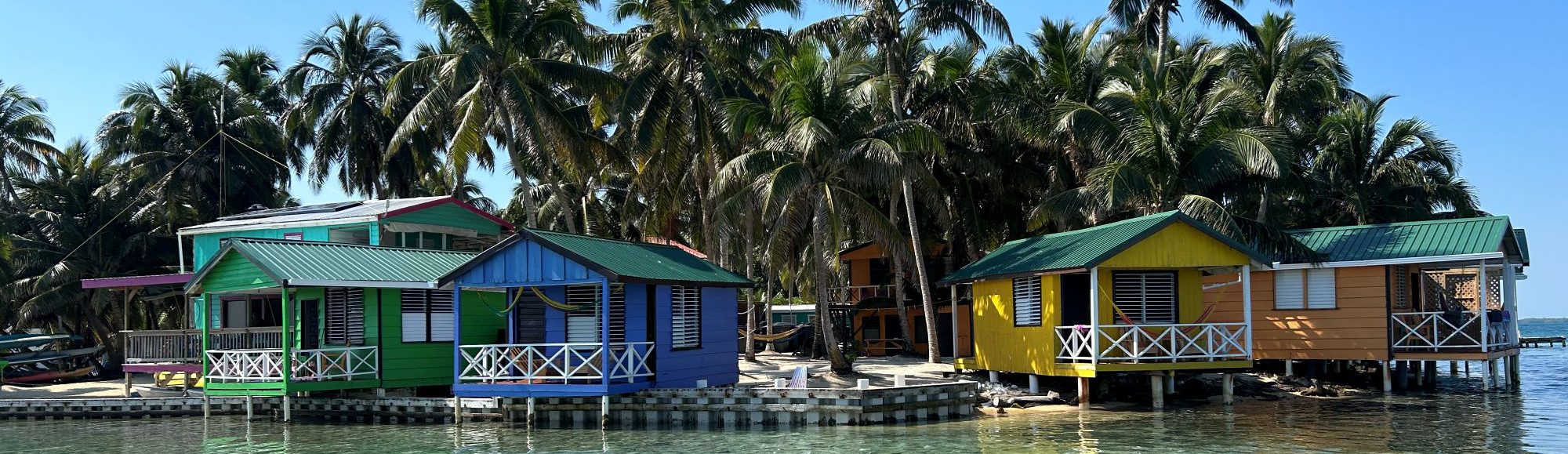 Rondreis-Belize-Tobacco-Caye-kleurige-houten-huisjes-aan-het-strand