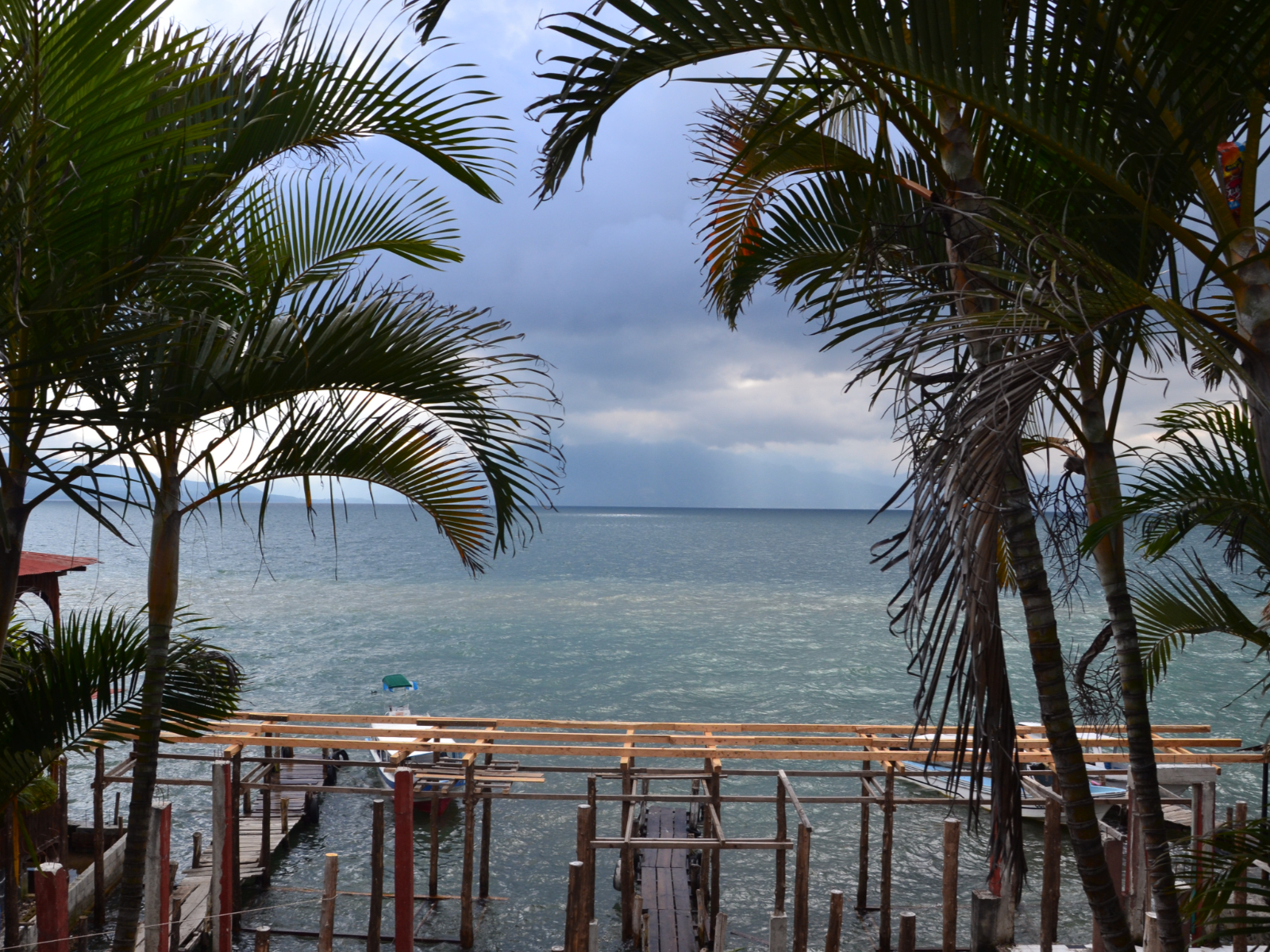 Rondreis Guatemala, Lake Atitlán Panajachel, uitzicht op meer met steiger en palmbomen