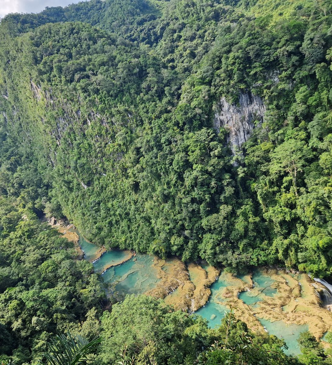 Rondreis Guatemala, Semuc Champey, uitzicht bovenaf met eromheen bomen en wolken
