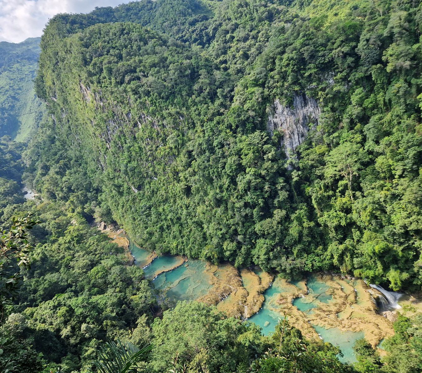 Rondreis Guatemala, Semuc Champey, uitzicht bovenaf met eromheen bomen en wolken