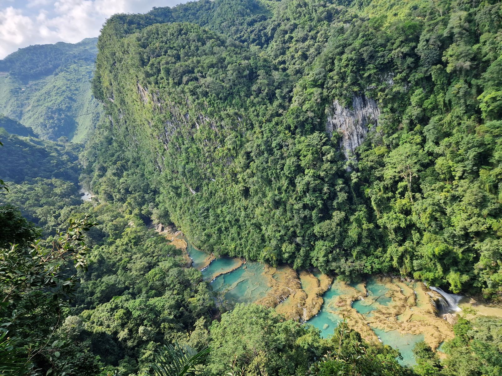 Rondreis Guatemala, Semuc Champey, uitzicht bovenaf met eromheen bomen en wolken