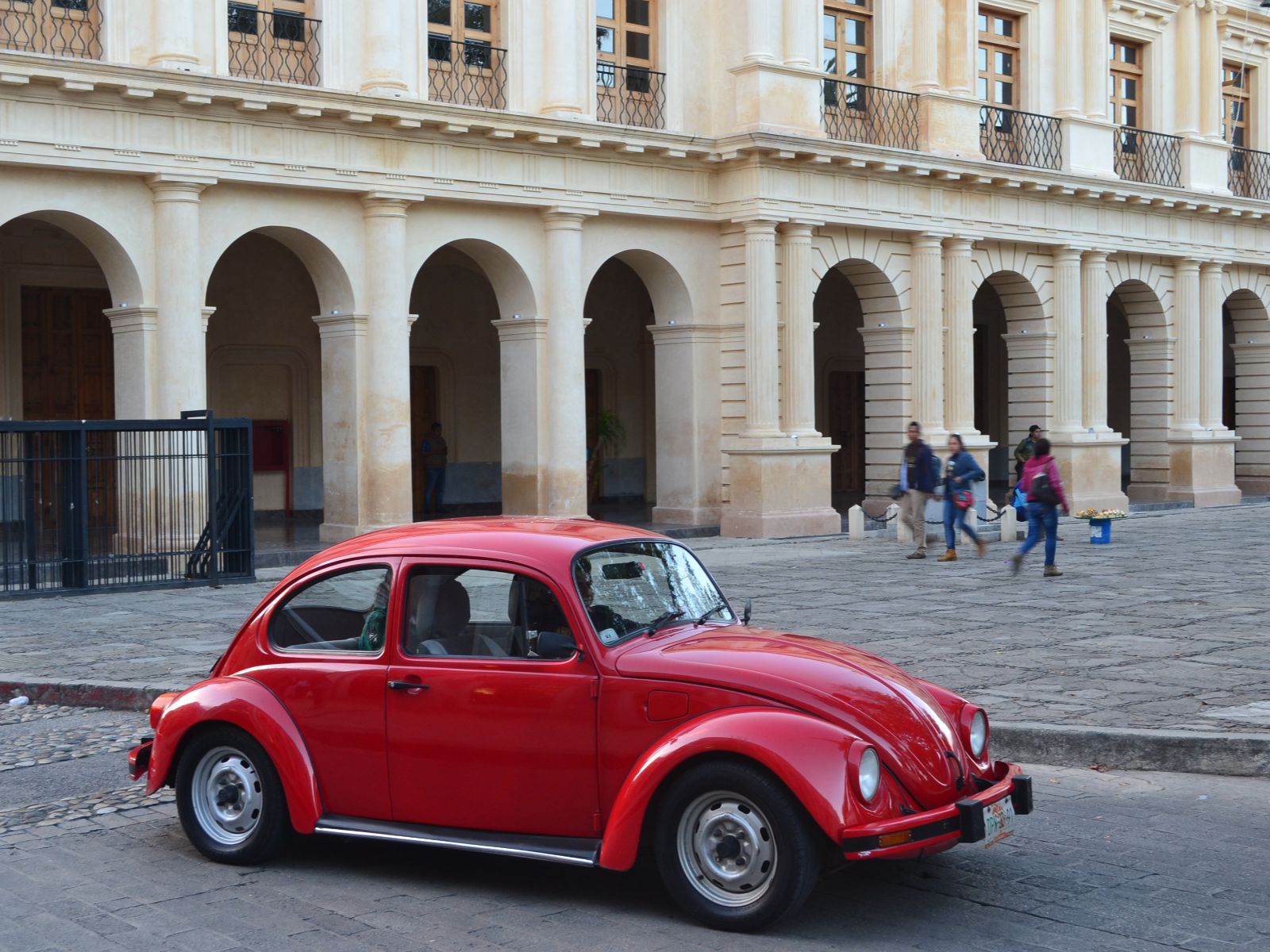 Rondreis Mexico, San Cristóbal de las Casas, rode auto met gebouw op de achtergrond
