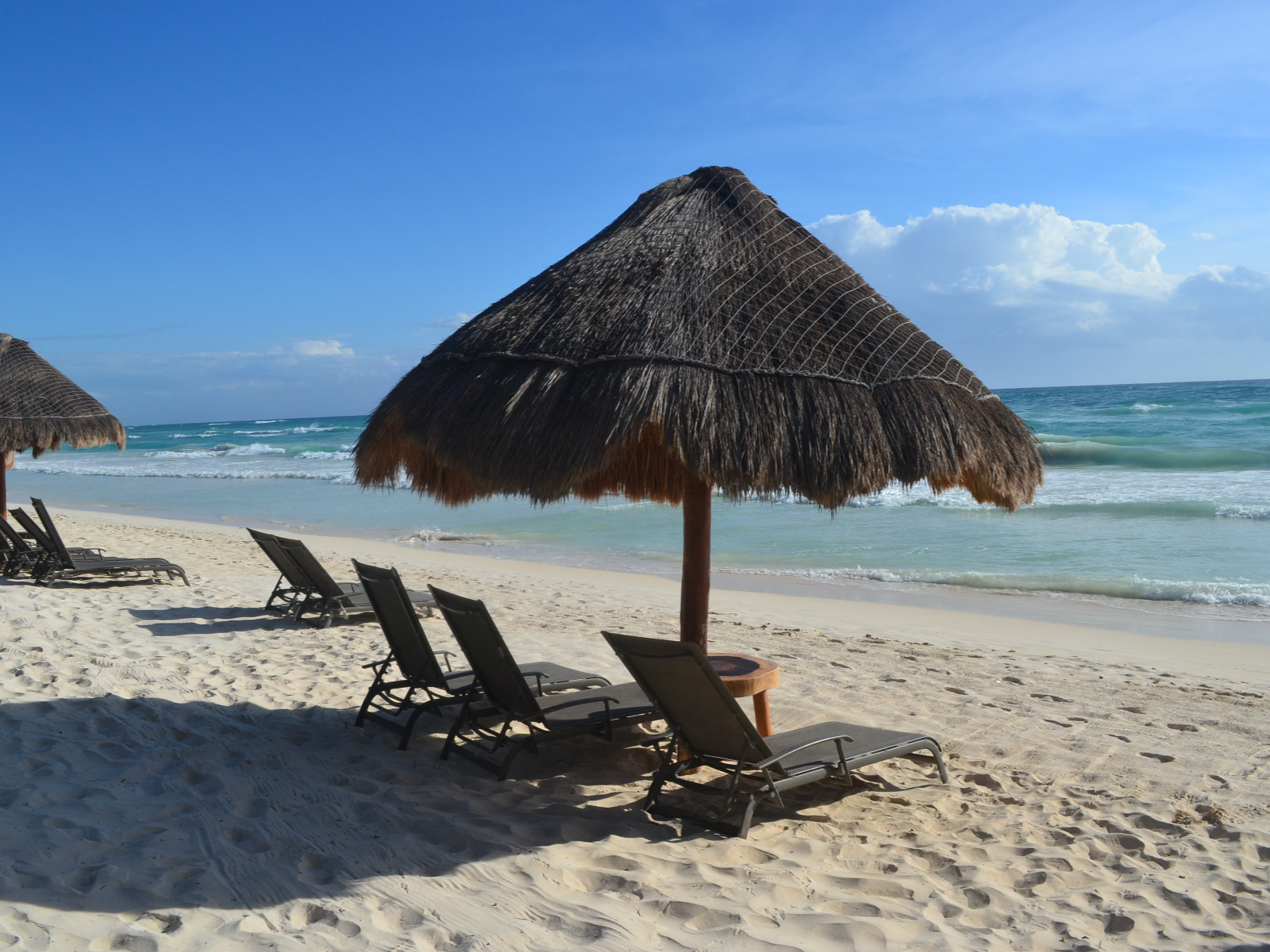 Rondreis Mexico, Tulum, stoelen op het strand onder rieten dak