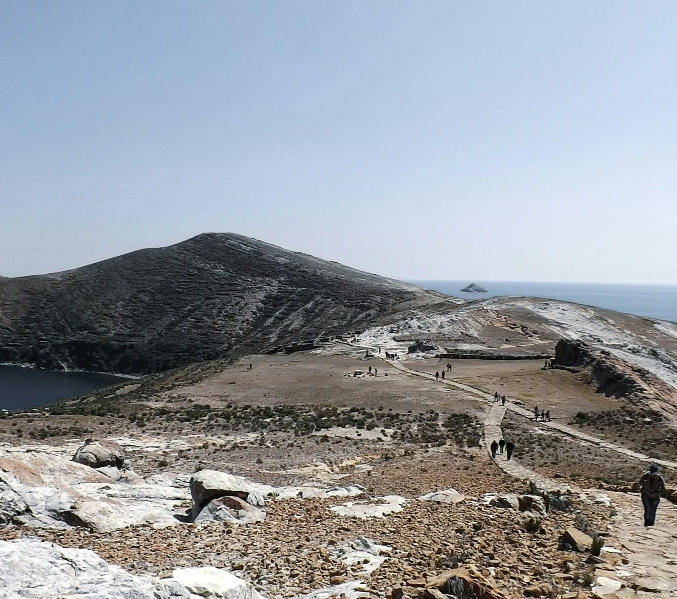 Rondreis Bolivia, Copacabana, excursie Mystiek Isla del Sol, rotsen met wandelpad en personen