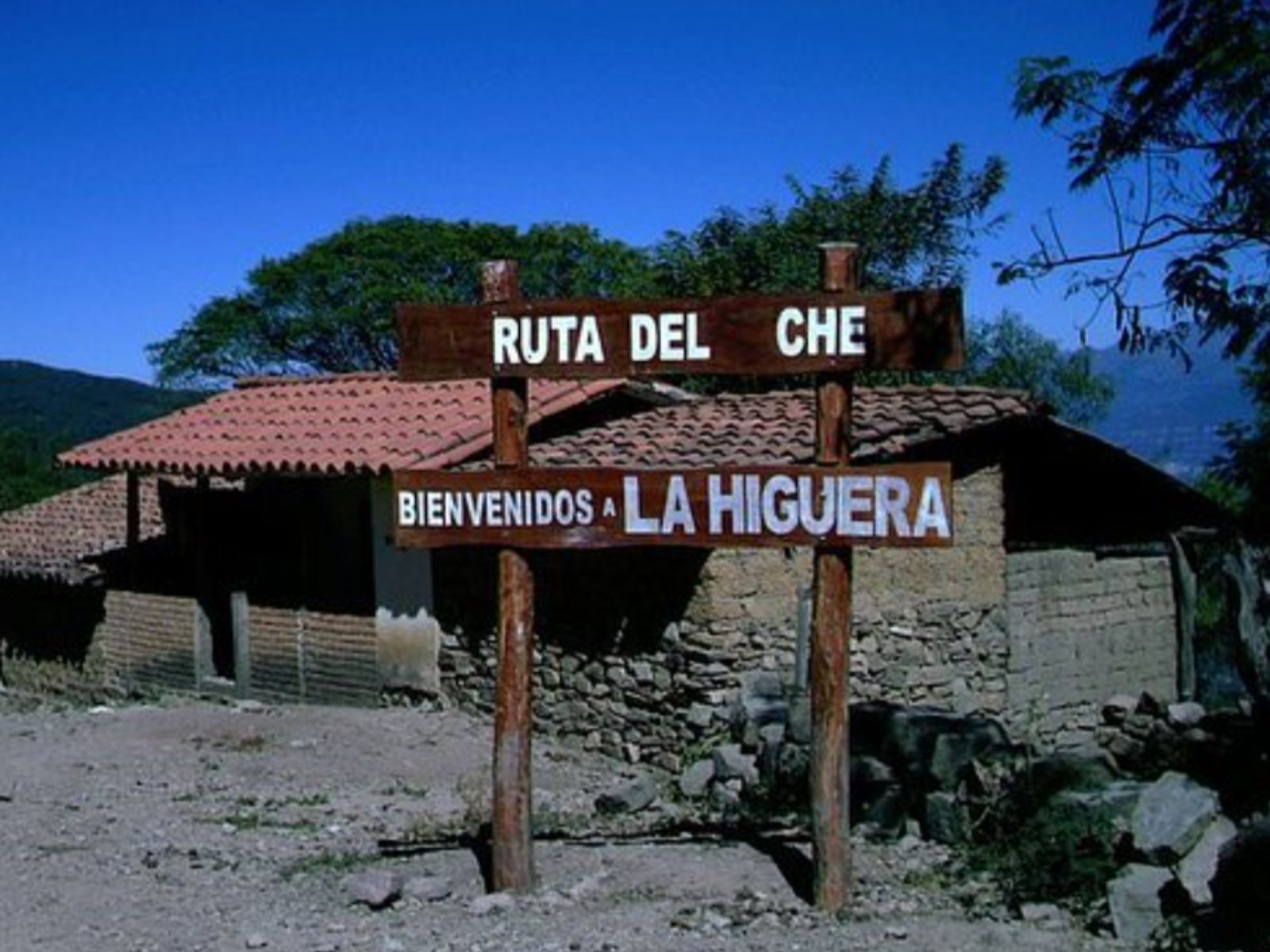 Rondreis Bolivia, Samaipata, excursie 4WD in de voetsporen van Che, wegwijzer met huisje en blauwe lucht op de achtergrond