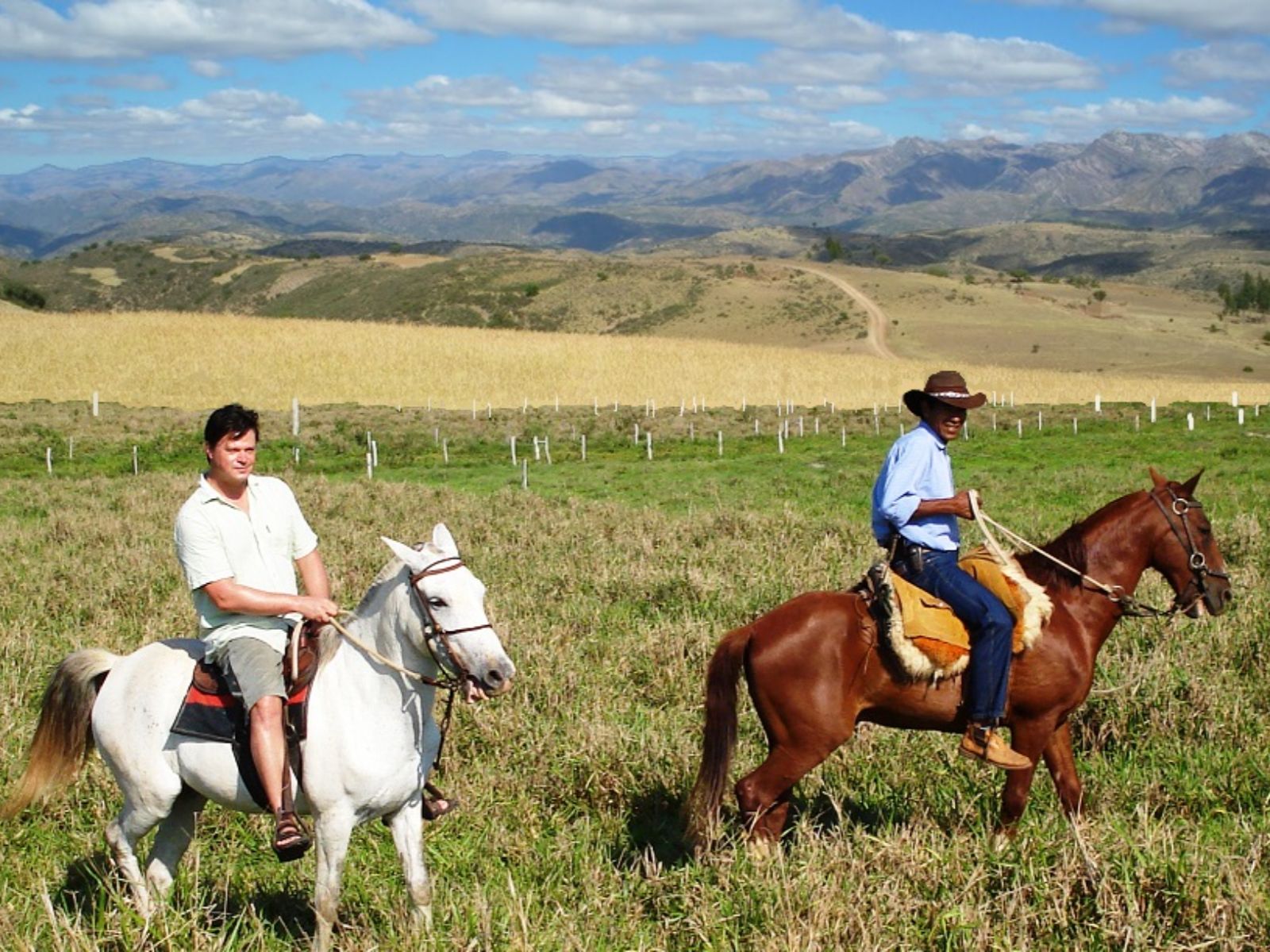 Rondreis Bolivia, Sucre, excursie te paard door de bergen rond Sucre, twee locals aan het paardrijden in gras