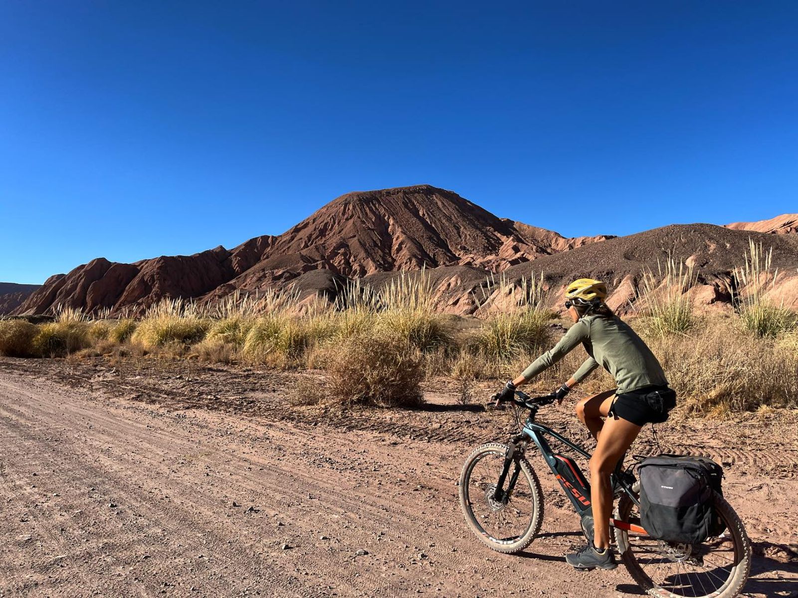 Rondreis Chili, San Pedro de Atacama, excursie fietsen door de woestijnvallei, fietser op weg met blauwe lucht