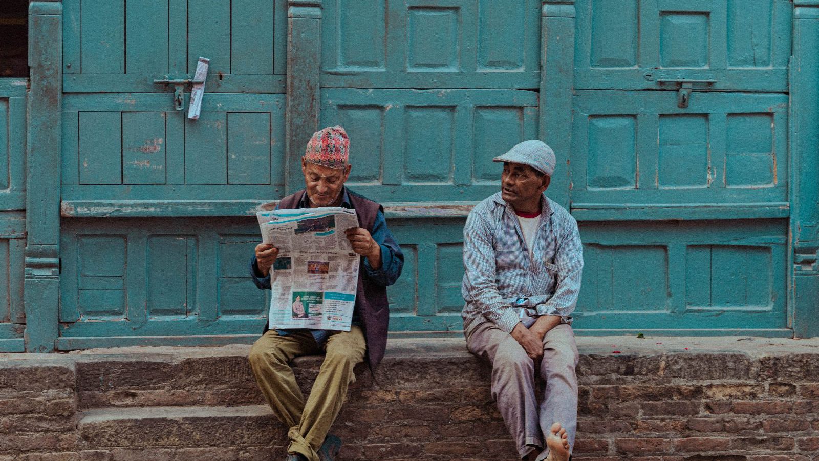Rondreis Nepal, Kathmandu, Mannen zitten voor deur op straat in Kathmandu