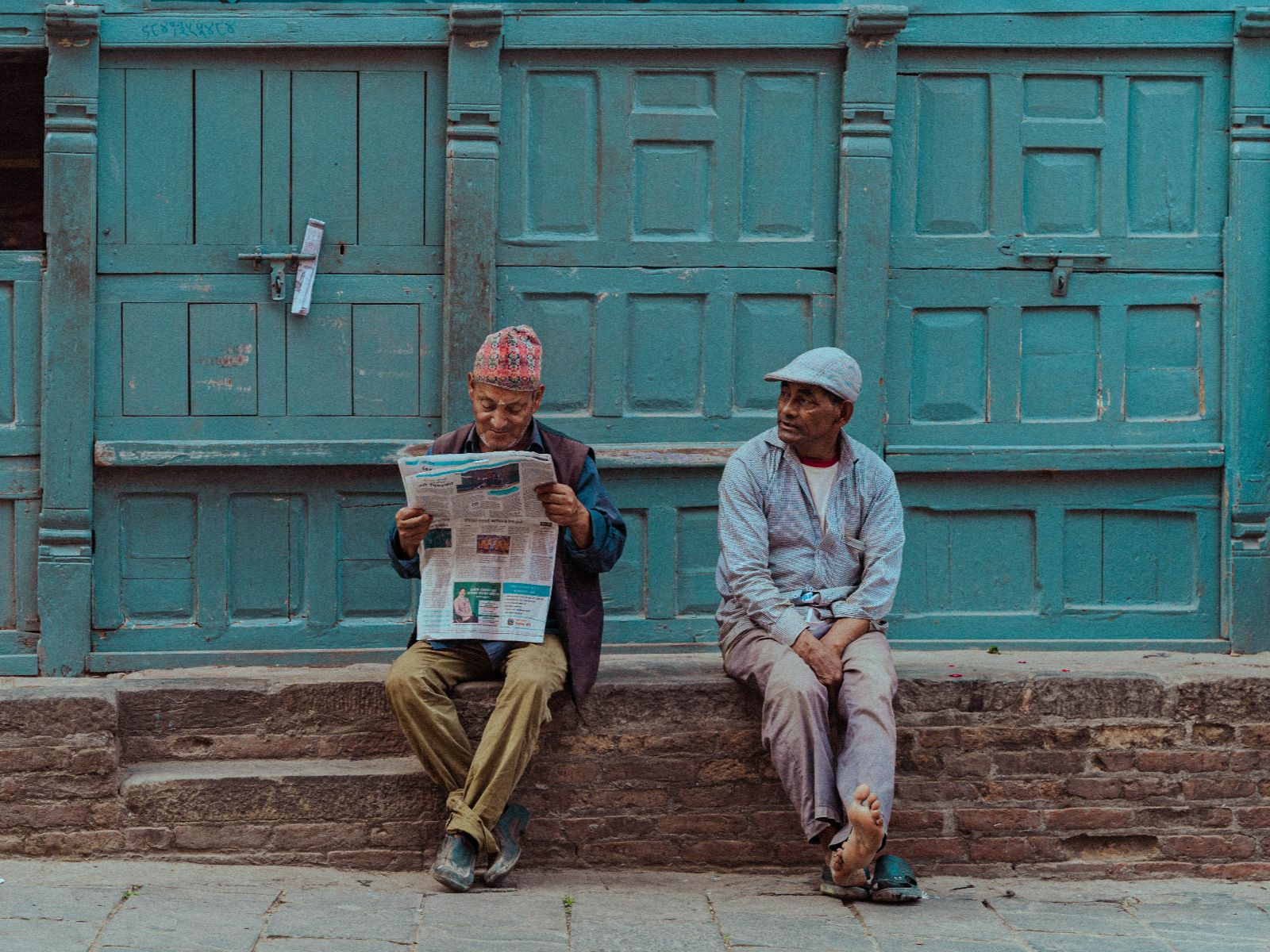 Rondreis Nepal, Kathmandu, Mannen zitten voor deur op straat in Kathmandu