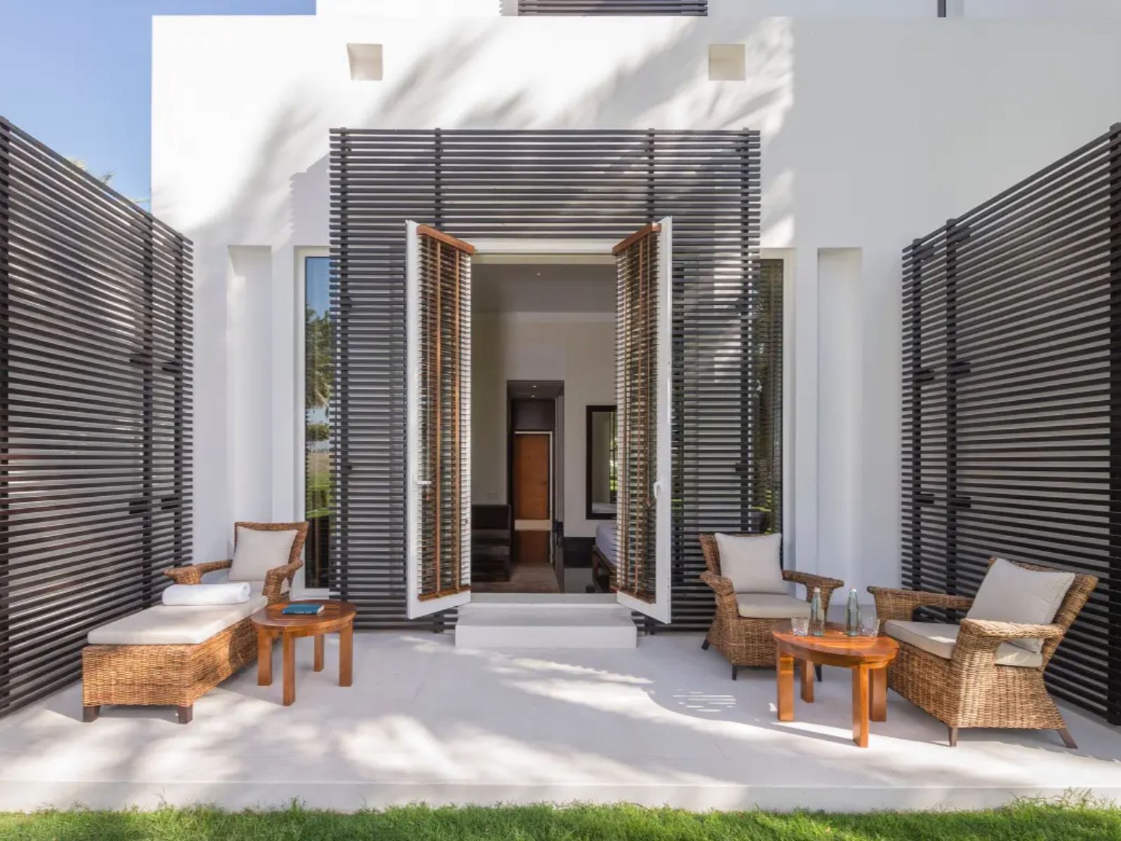 Rondreis Oman, Muscat, The Chedi, hotelkamer van buitenaf met openslaande deuren en zitgedeelte