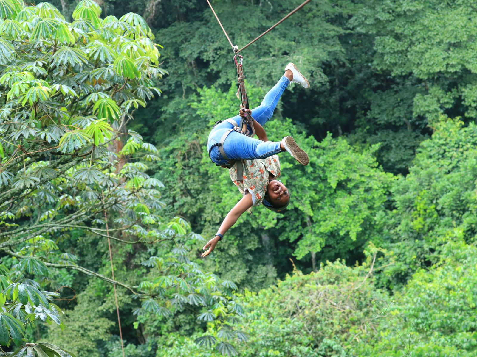 Rondreis Costa Rica, La Fortuna, excursie Arenal Sky Adventure Ziplines, zipline vrouw hangt op kop aan zipline