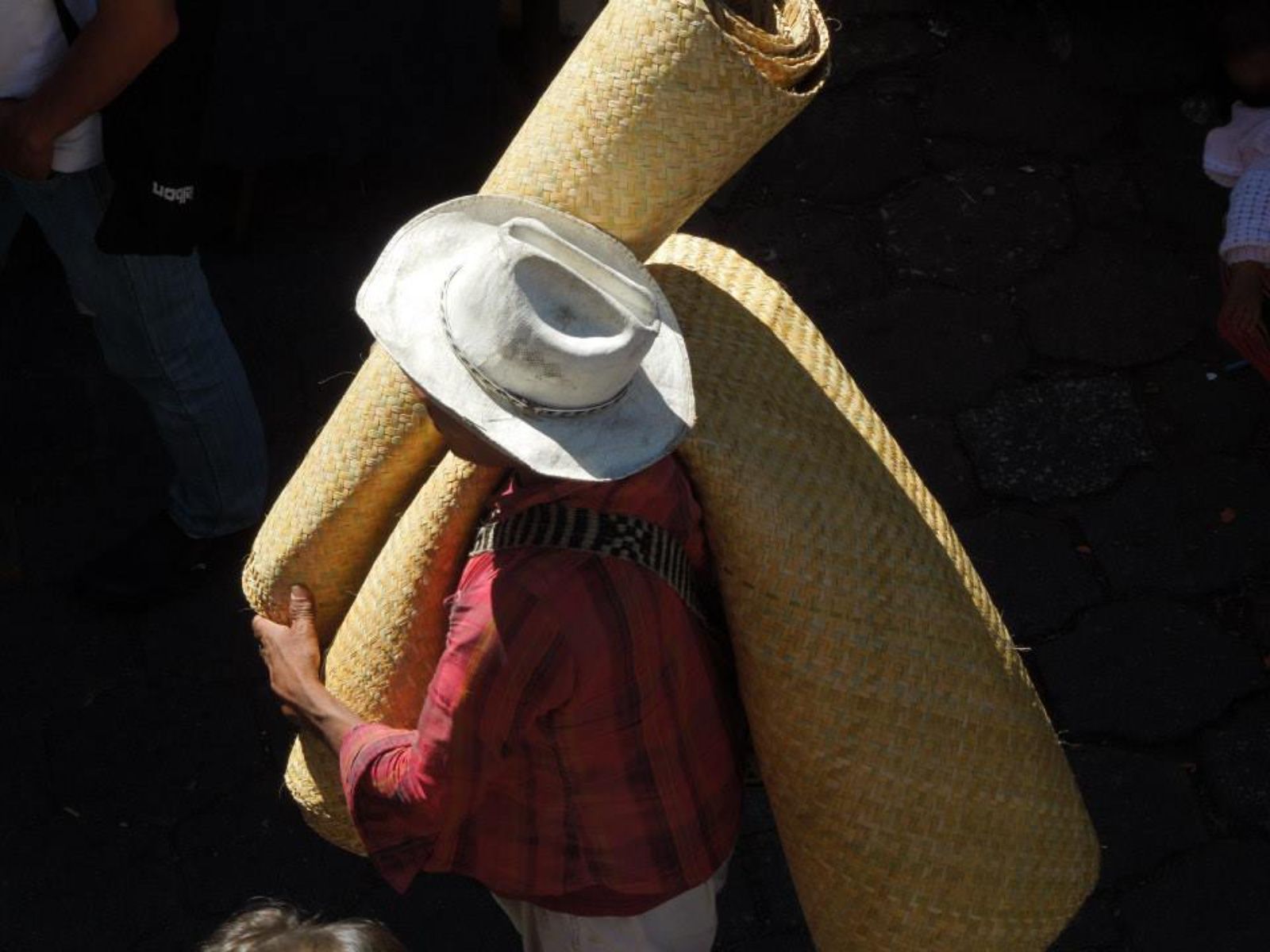 Rondreis Guatemala, Antigua, excursie bezoek Chichicastenango, man met matten op de markt