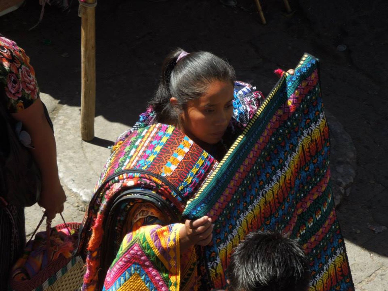 Rondreis Guatemala, Antigua, excursie bezoek Chichicastenango, vrouw met kleedjes op de markt