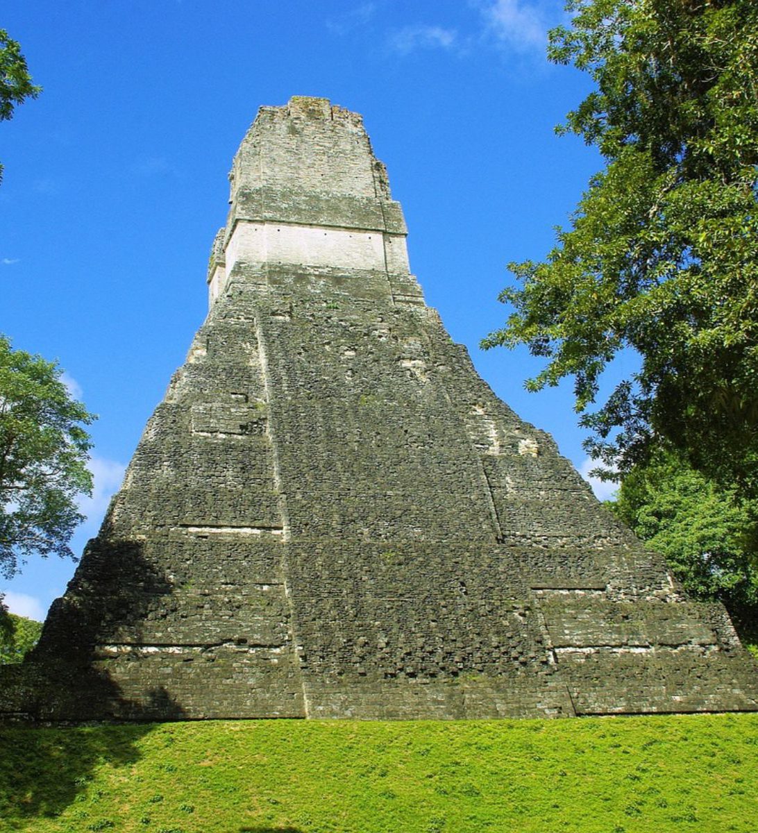 Rondreis Guatemala, Flores, excursie zonsopkomst in Tikal, ruïne met gras rondom