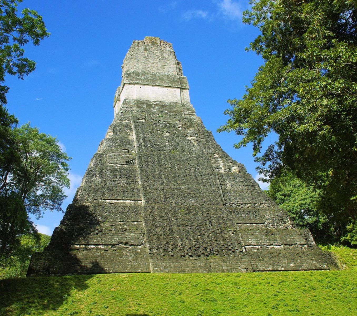 Rondreis Guatemala, Flores, excursie zonsopkomst in Tikal, ruïne met gras rondom