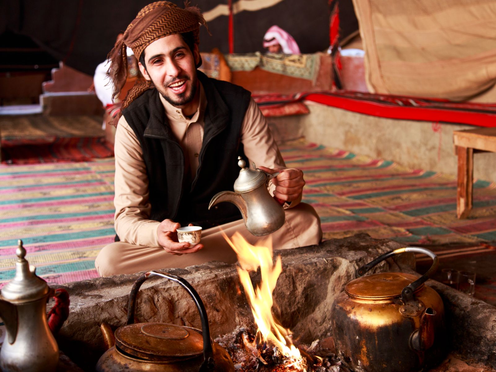 Rondreis Jordanië, Wadi Rum, excursie koffie en verhalen bij Bedoeïnen, man schenkt thee in