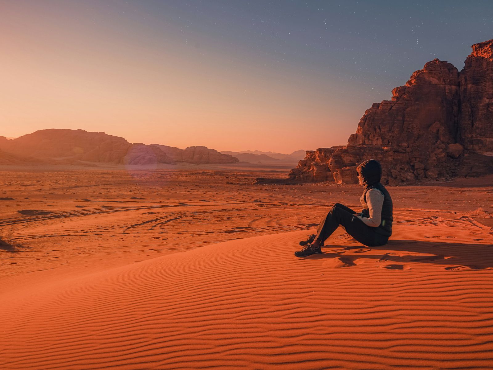 Rondreis Jordanië, Wadi Rum, excursie sterrenkijken Wadi Rum, vrouw op zandheuvel zonsondergang