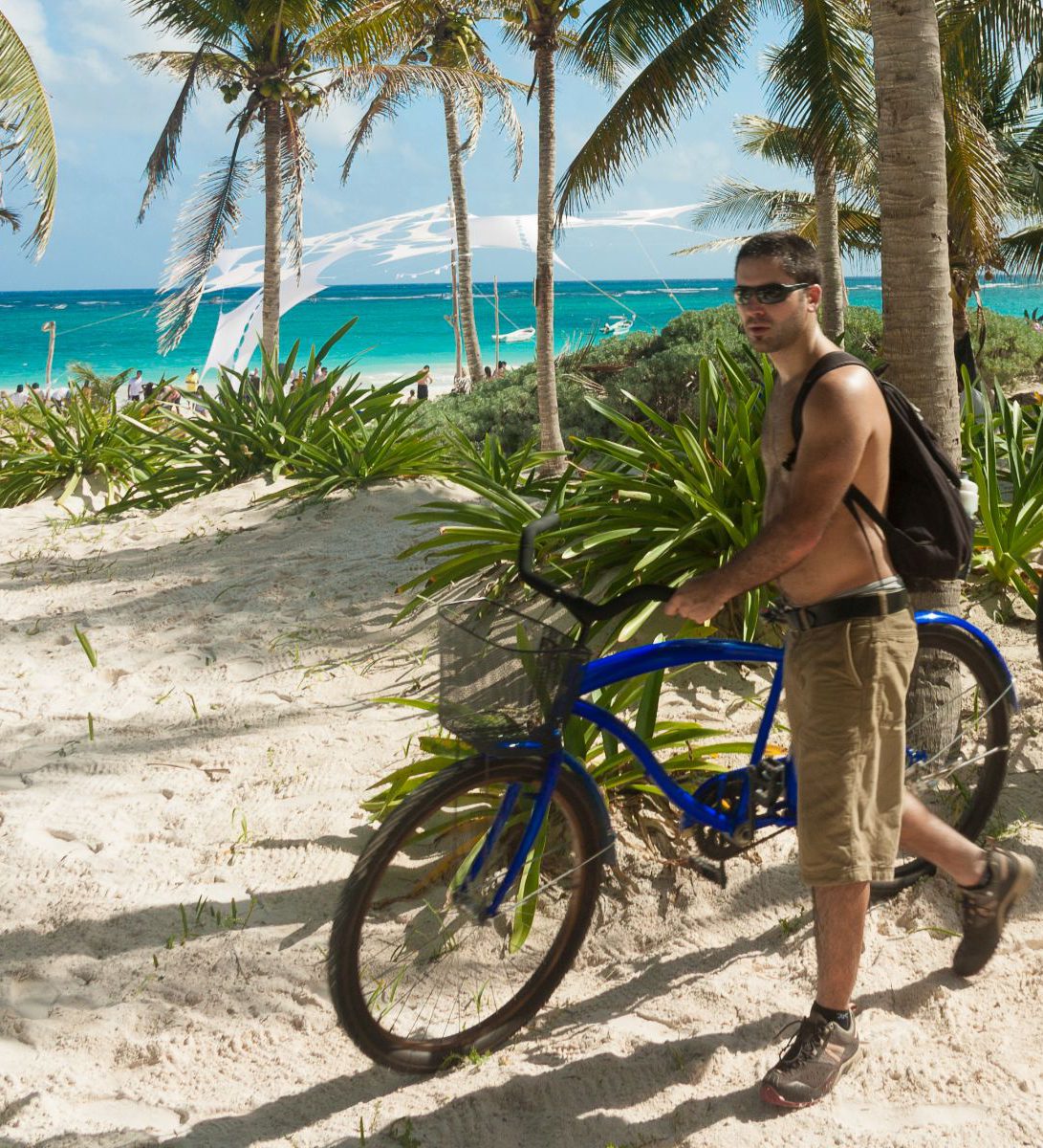 Rondreis Mexico, Tulum, Excursie Fietstour door Tulum, twee fietsers op het strand met palmbomen