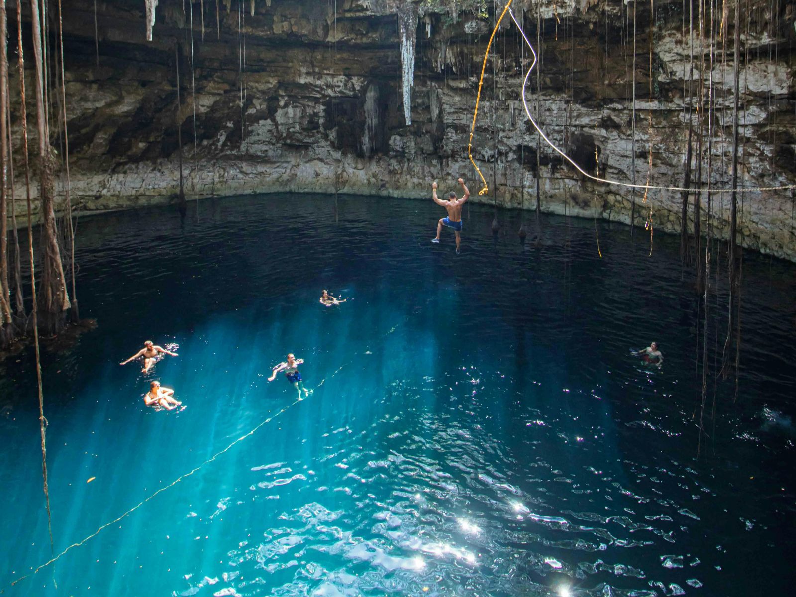 Rondreis Mexico, Valladolid, Op de fiets langs cenotes en de Maya-cultuur, cenote met blauw water en zwemmende mensen