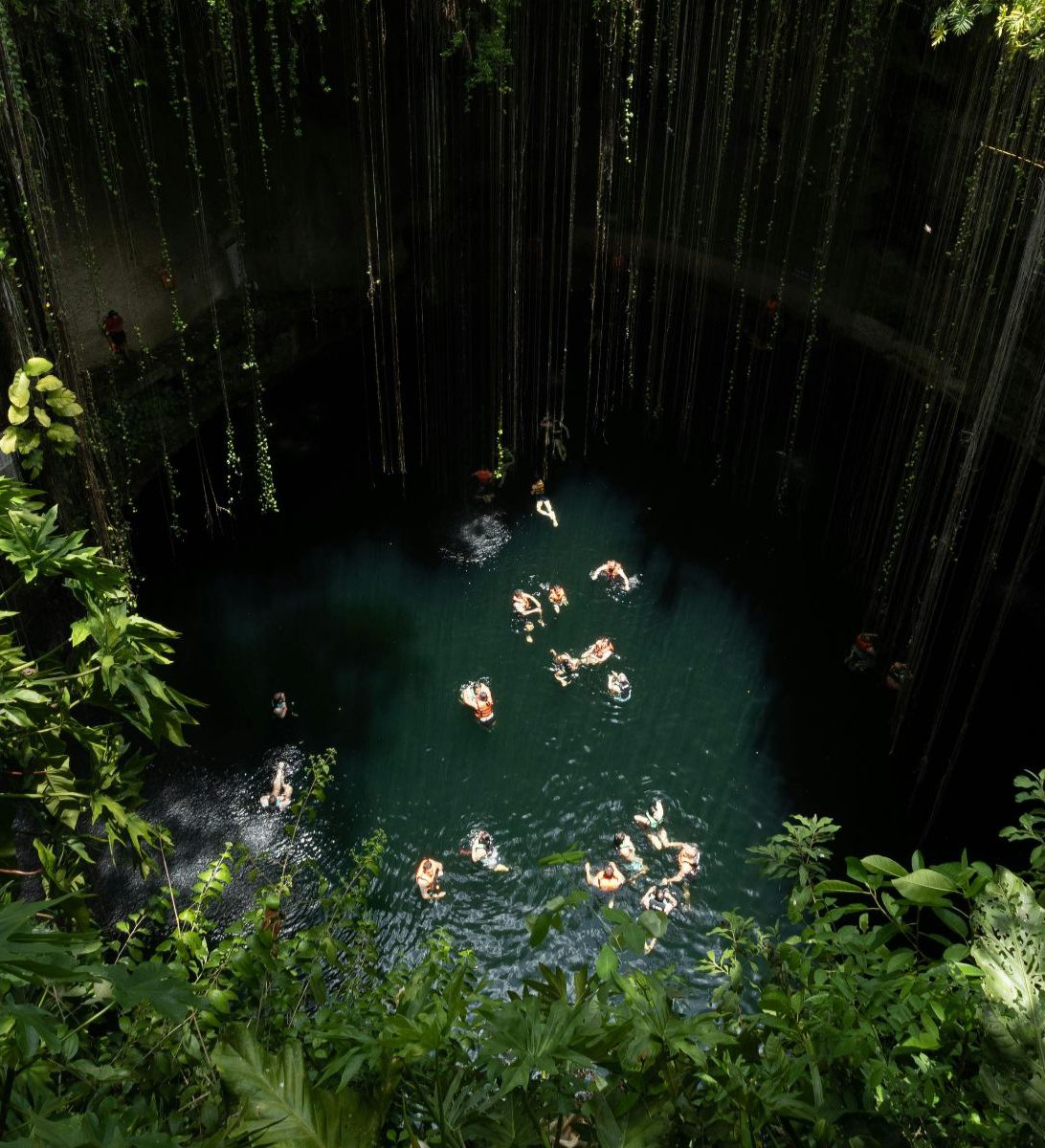 Rondreis Mexico, Valladolid, Op de fiets langs cenotes en de Maya-cultuur, cenote van bovenaf met zwemmende mensen