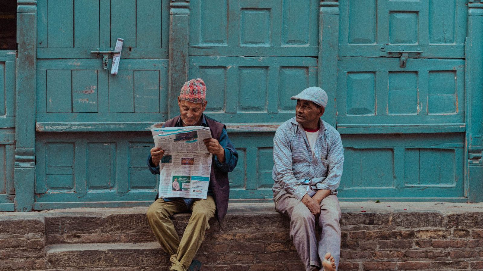 Rondreis Nepal, Kathmandu, Mannen zitten voor deur op straat in Kathmandu
