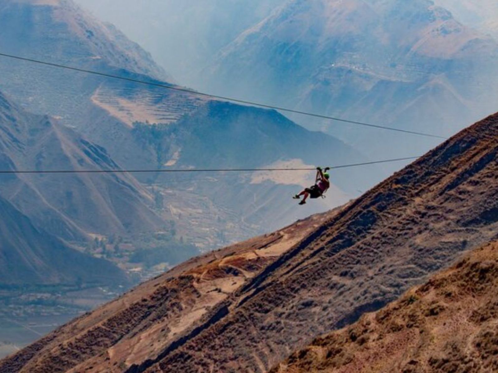 Rondreis Peru, Cusco, excursie ziplinen boven de Heilige Vallei, persoon hangt aan zipline