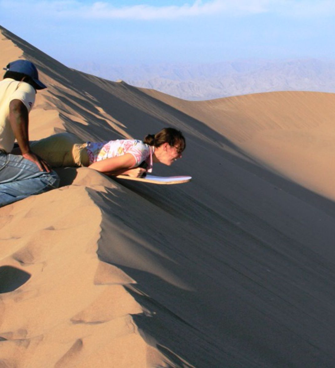 Rondreis Peru, Ica, excursie sandboarden en buggyrijden in Huacachina, persoon sandboarden