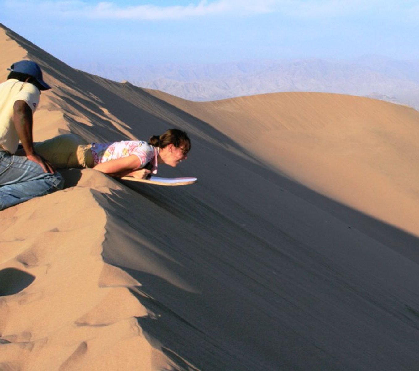 Rondreis Peru, Ica, excursie sandboarden en buggyrijden in Huacachina, persoon sandboarden