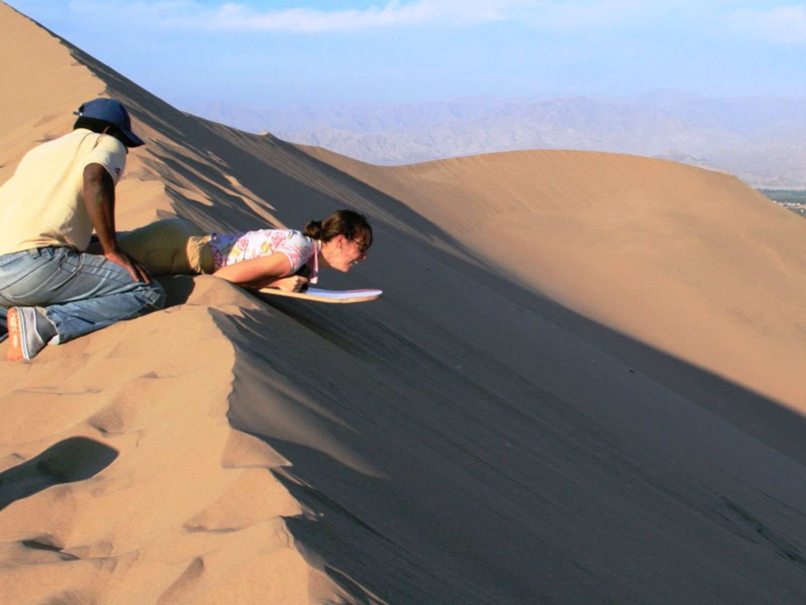 Rondreis Peru, Ica, excursie sandboarden en buggyrijden in Huacachina, persoon sandboarden