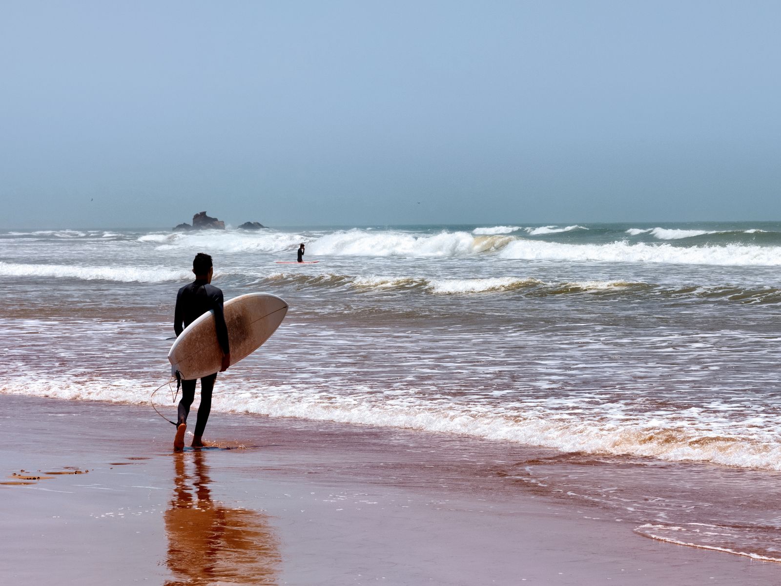 Rondreis Marokko, Essaouria, excursie surfen, man met surfboard op strand
