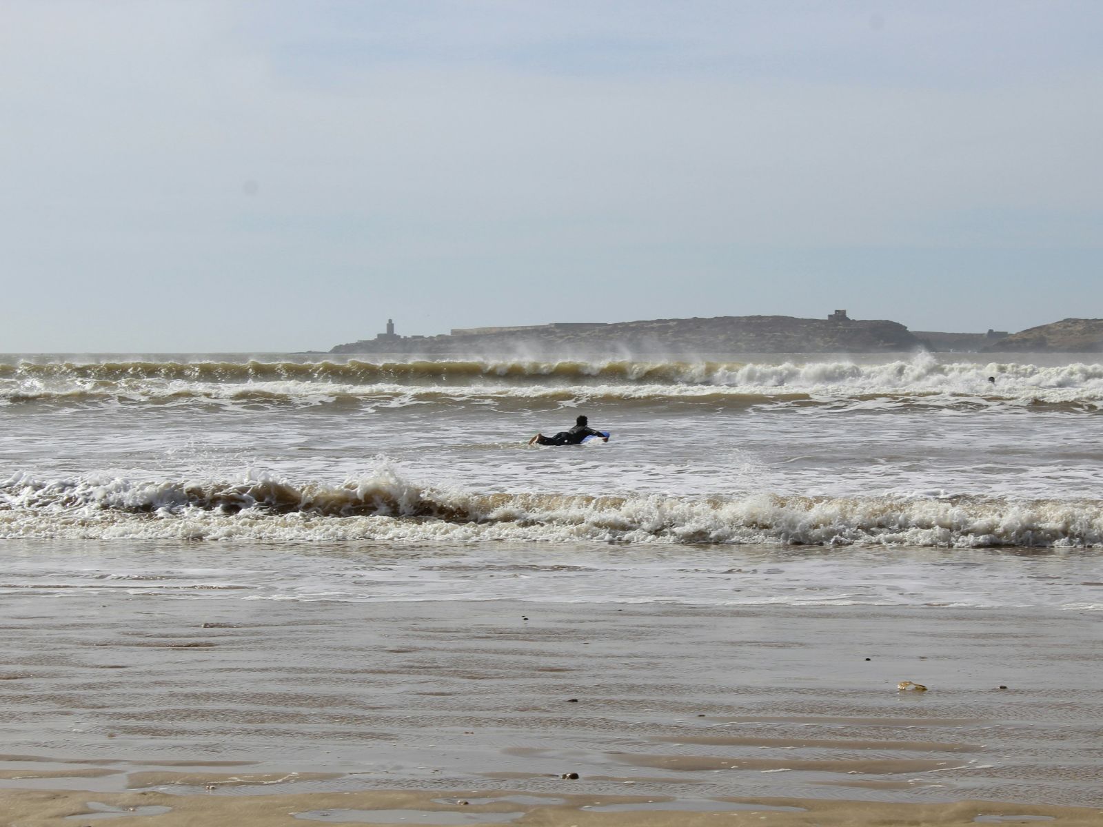 Rondreis Marokko, Essaouria, excursie surfen, surfer op surfplank in zee