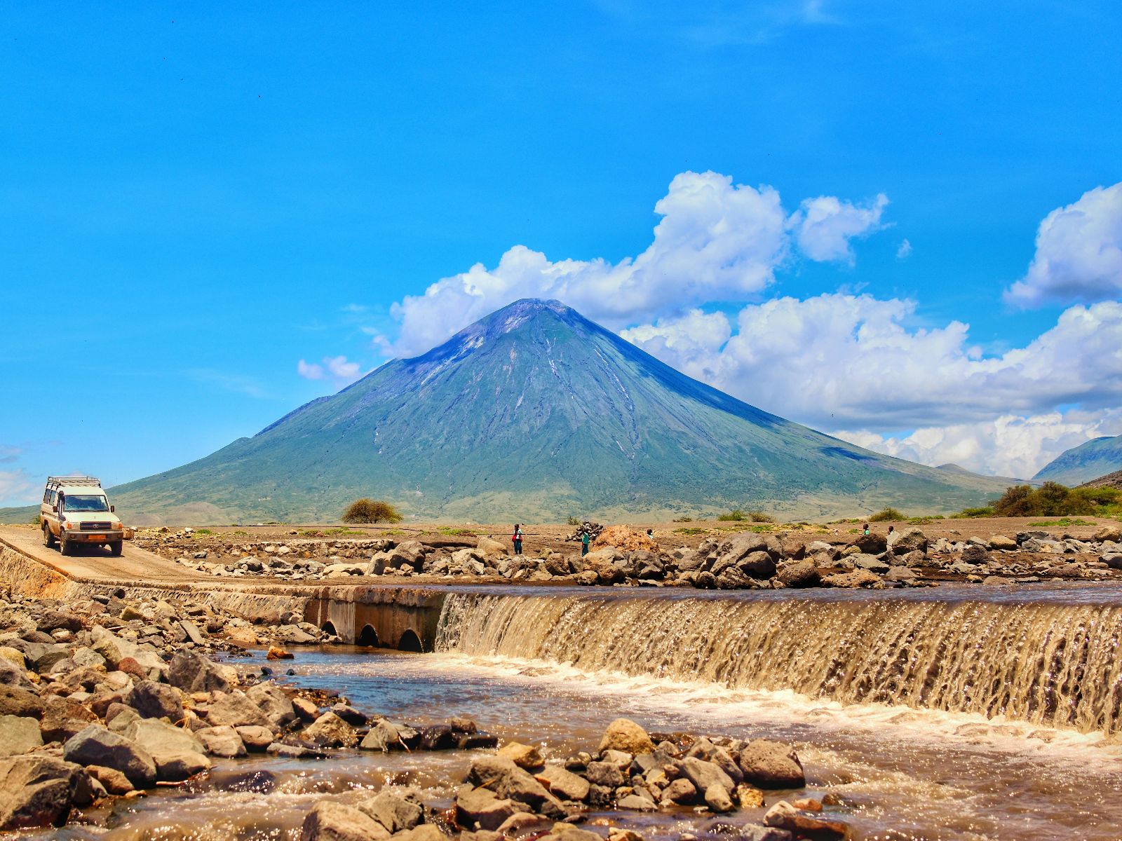 Rondreis Tanzania, Arusha, excursie mountainbiken bij Mt Meru, auto op de weg met Mt Meru
