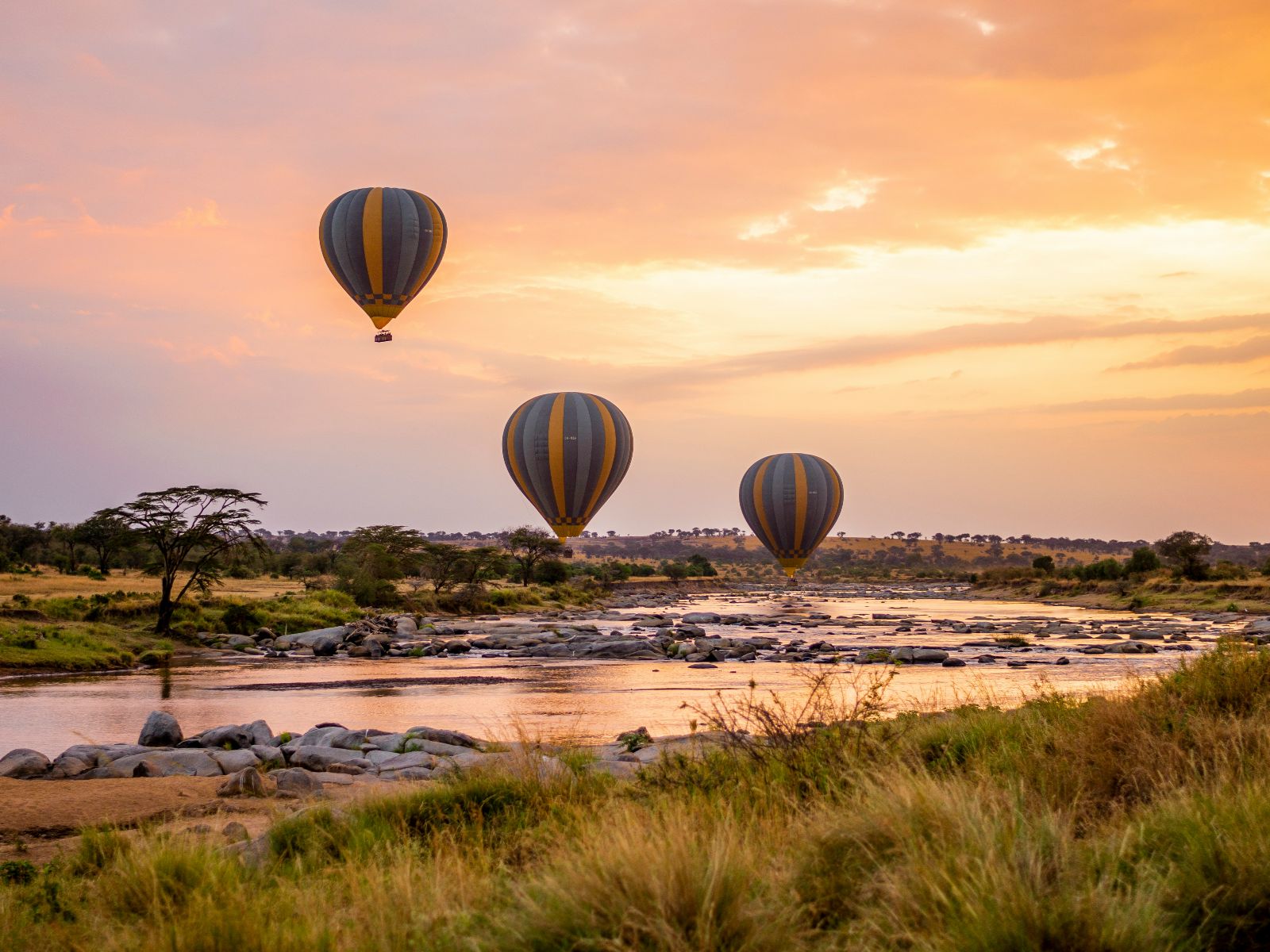 Rondreis Tanzania, Serengeti, excursie ballonvaart over Serengeti, luchtballonnen boven rivier tijdens schemering