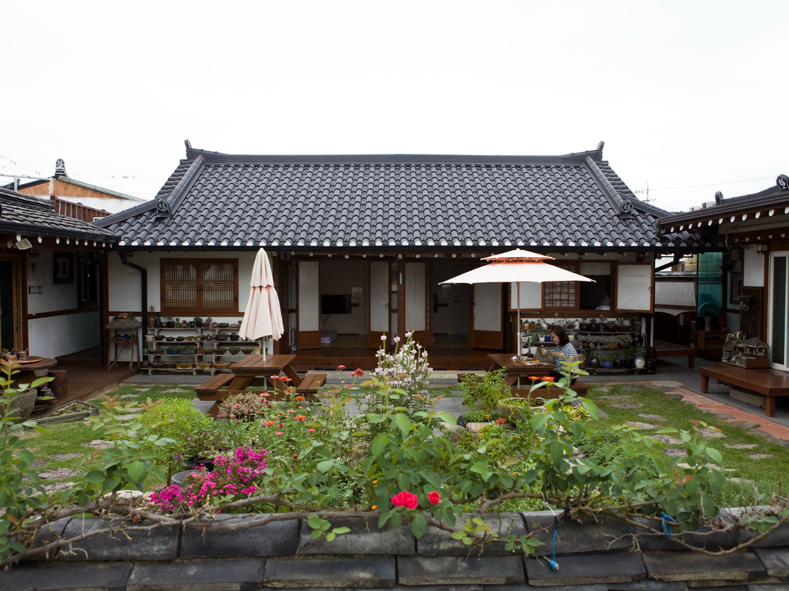 Rondreis Zuid-Korea, Gyeongju, Raon Hanok Stay, Tuin met tafels en buitenaanzicht van de kamers