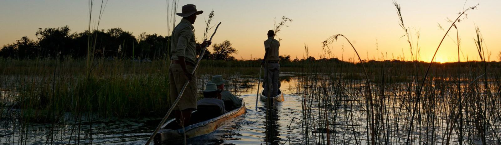 Rondreis-Botswana-Maun-excursie-Full-Day-Mokoro-Tour-twee-locals-op-de-bootjes-aspect-ratio-1512-438